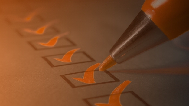 A close-up of a pen writing a check mark for earnings season checklist in preparation for financial evaluation