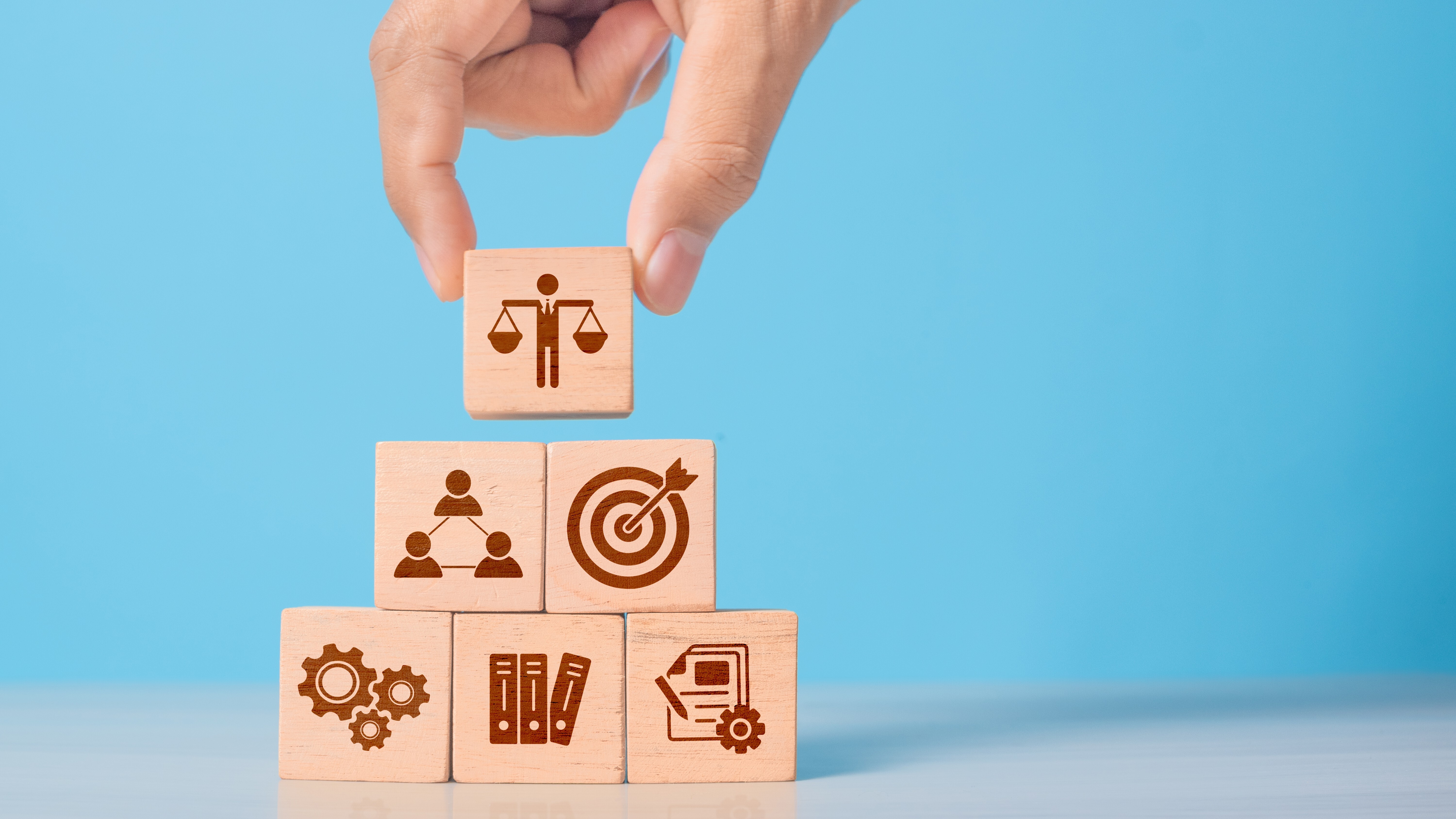 Wooden cube with ethics symbol held in hand. Represents corporate responsibility, integrity, and compliance in business practices.