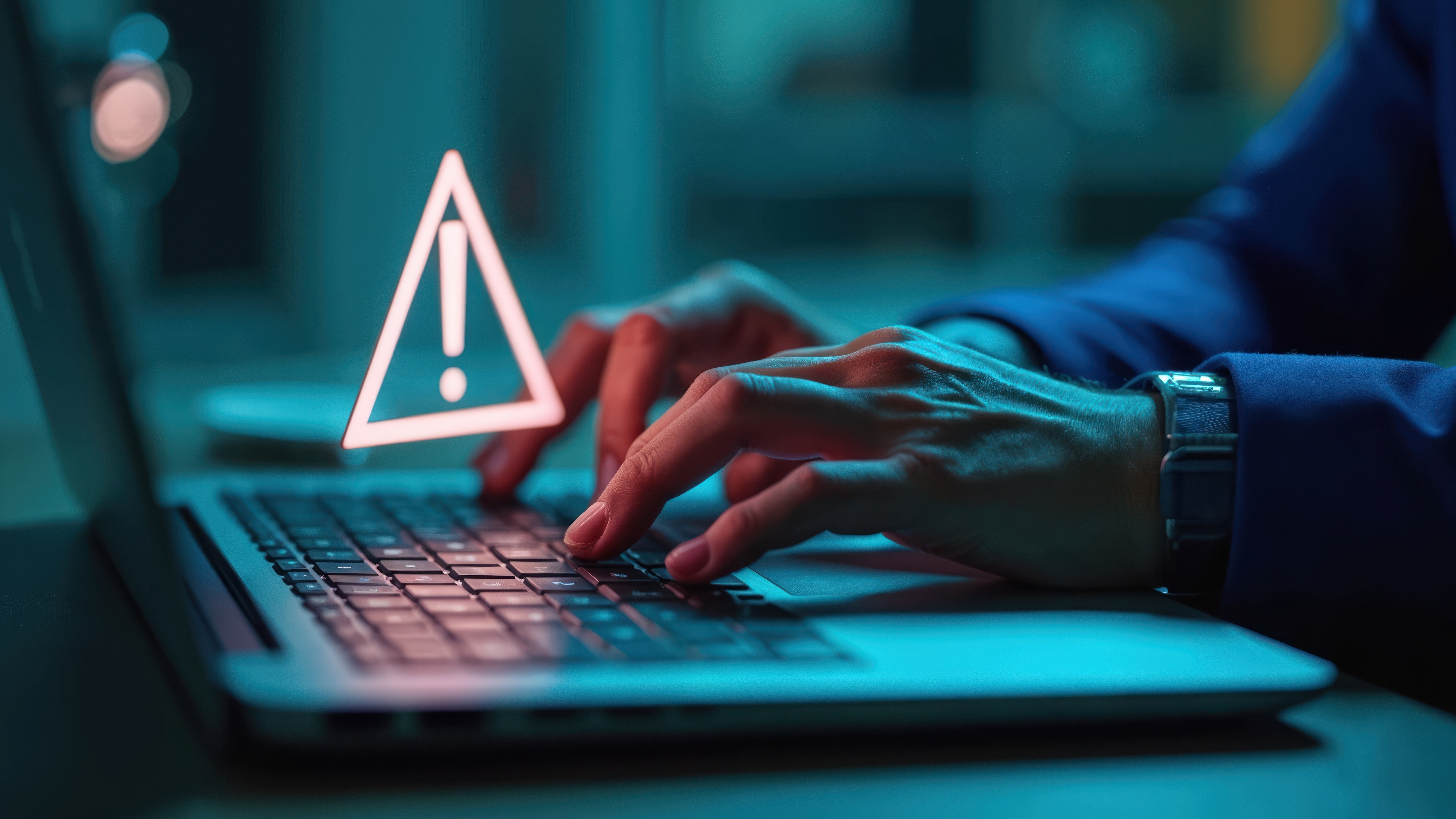 Hands typing on laptop keyboard with warning alert symbol. Error message, cyber attack, data breach concept. Hacker alert, caution of system compromised. Business data security