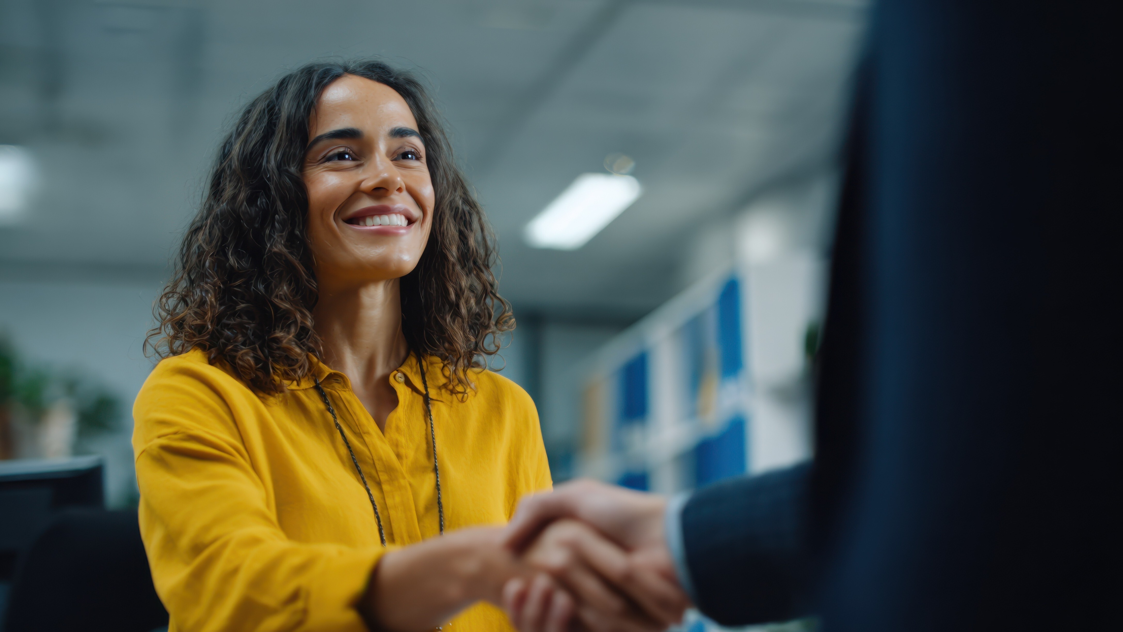 Medium shot capturing a studentathletes focused expression while shaking hands with a compliance officer after signing a NIL contract with office shelves softly blurred.