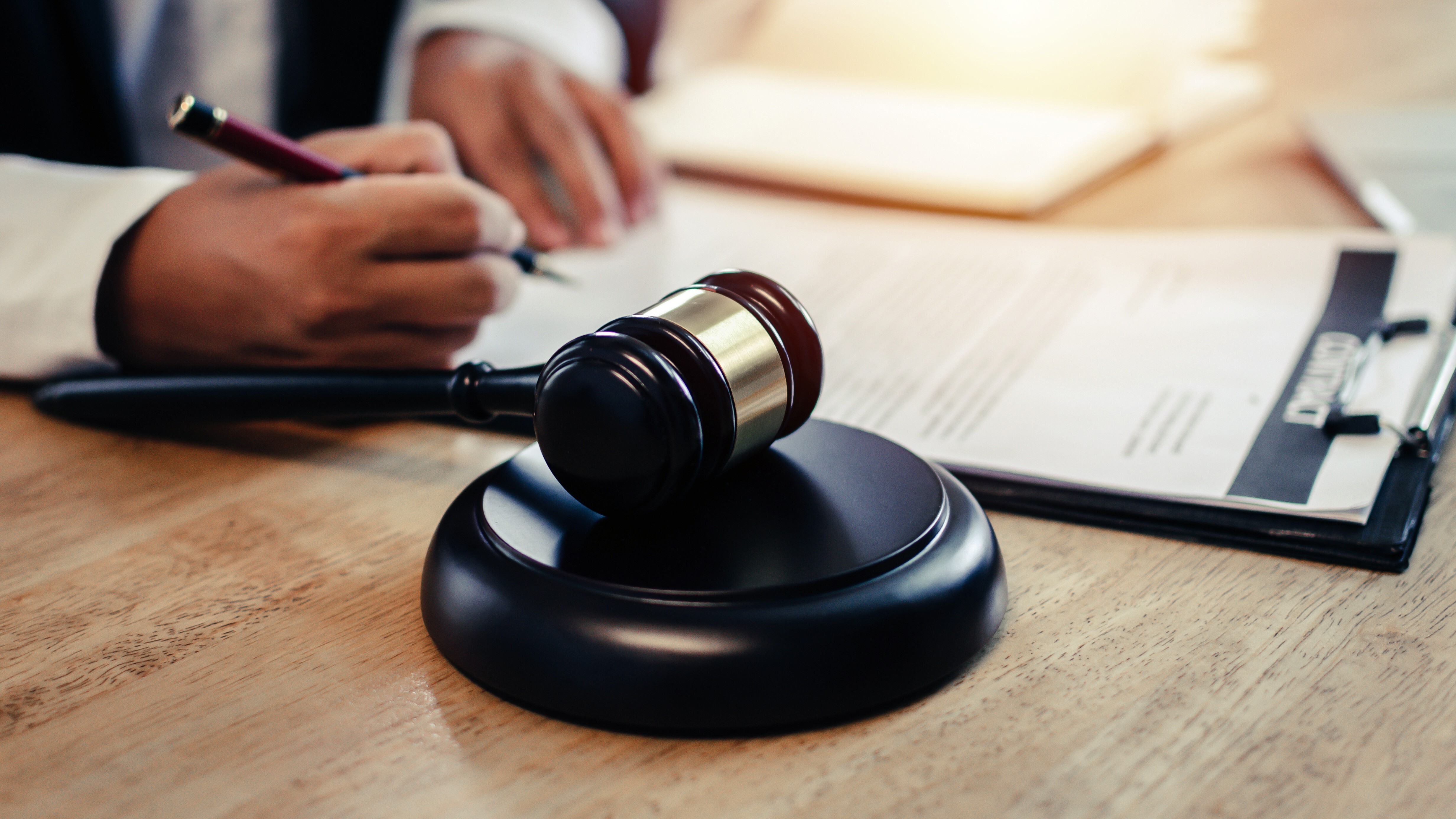 justice lawyer in black suit working about legal legislation with documents on workplace and wooden judge gavel on desk in courtroom office, business adviser, justice law and legal service concept