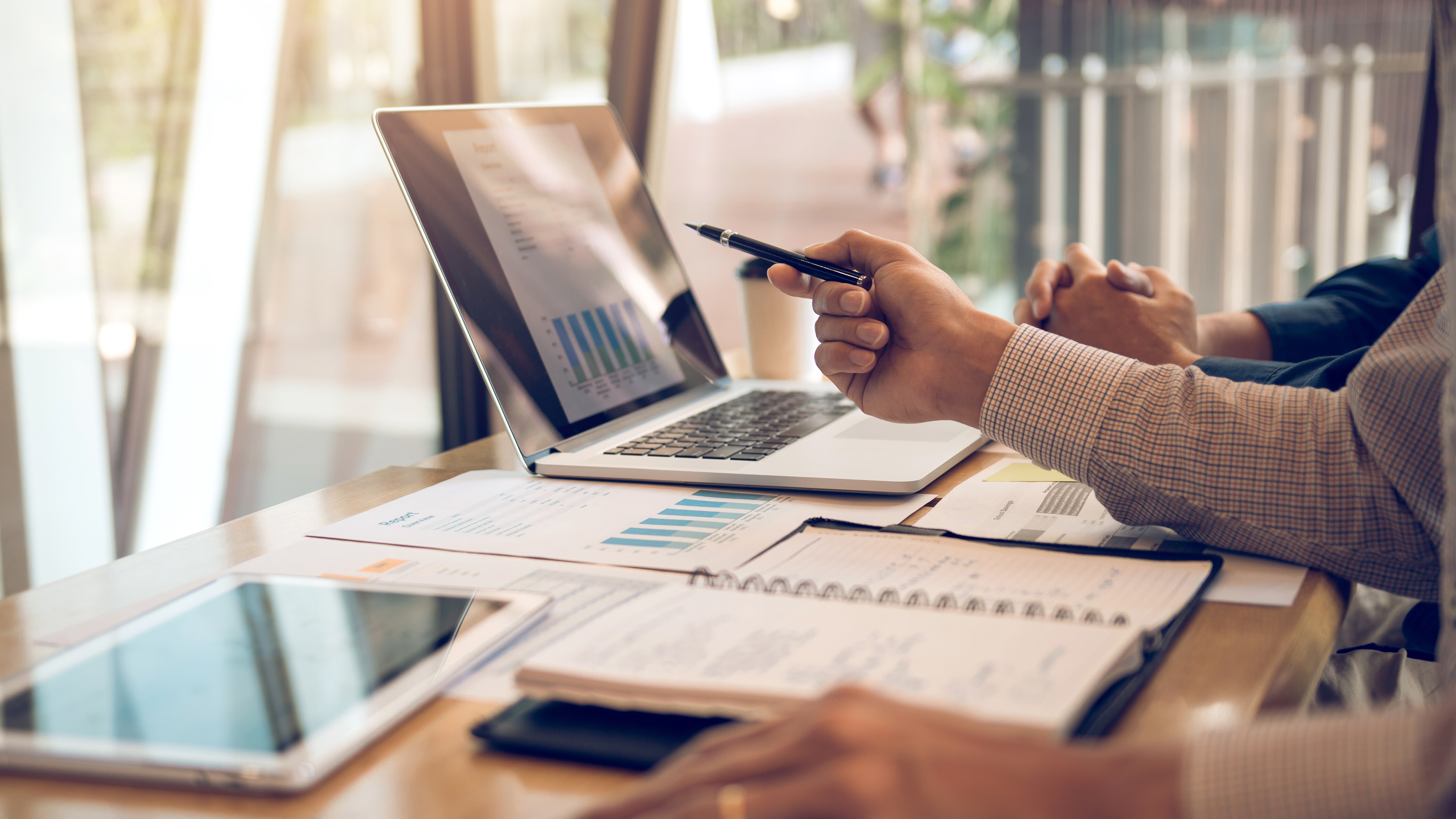 Business partnership pointing to the graph of the company financial statements report and profits earned during in the computer screen with giving a presentation to colleagues in office room.