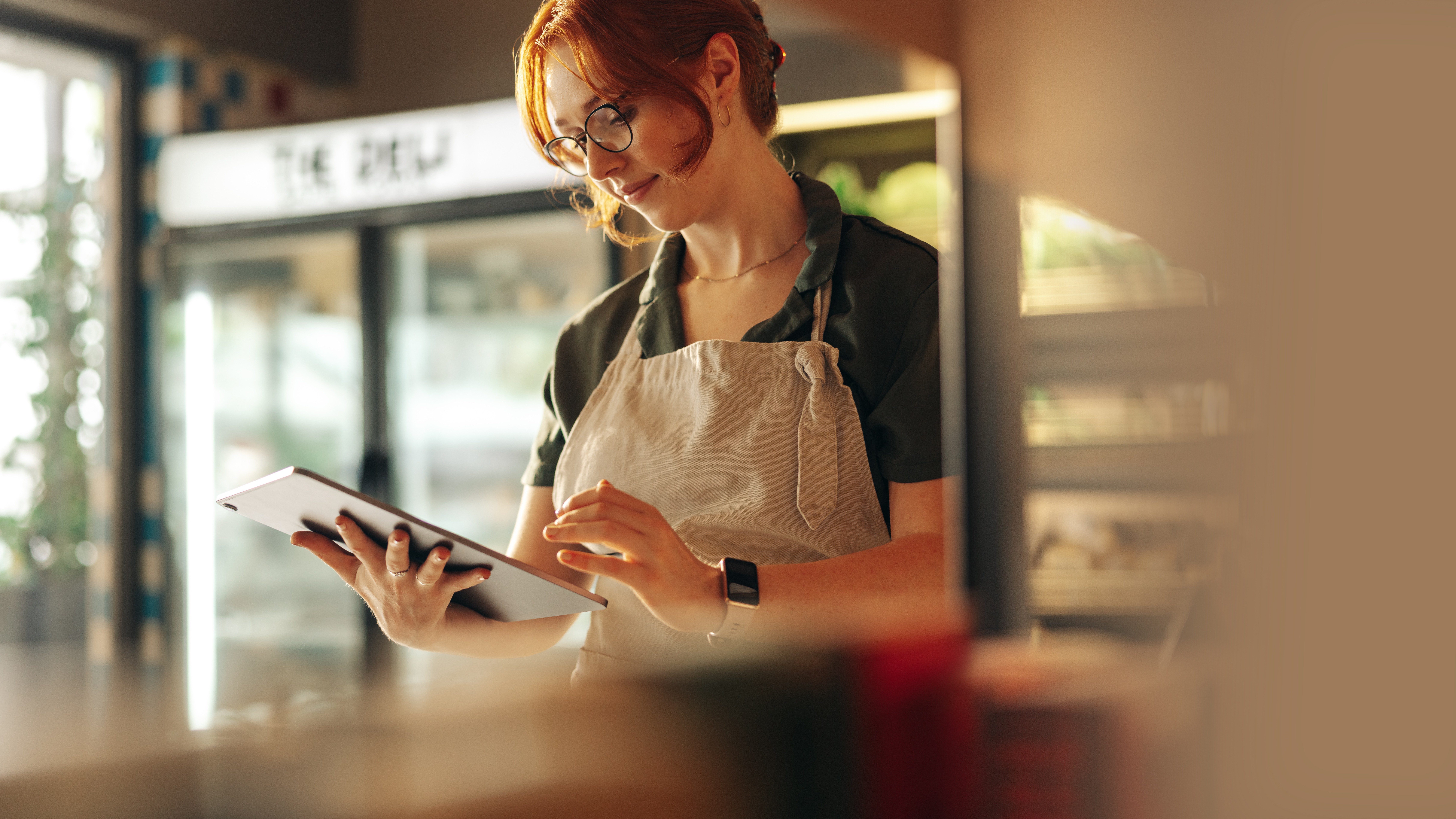 Cheerful store owner using a digital tablet in her grocery store