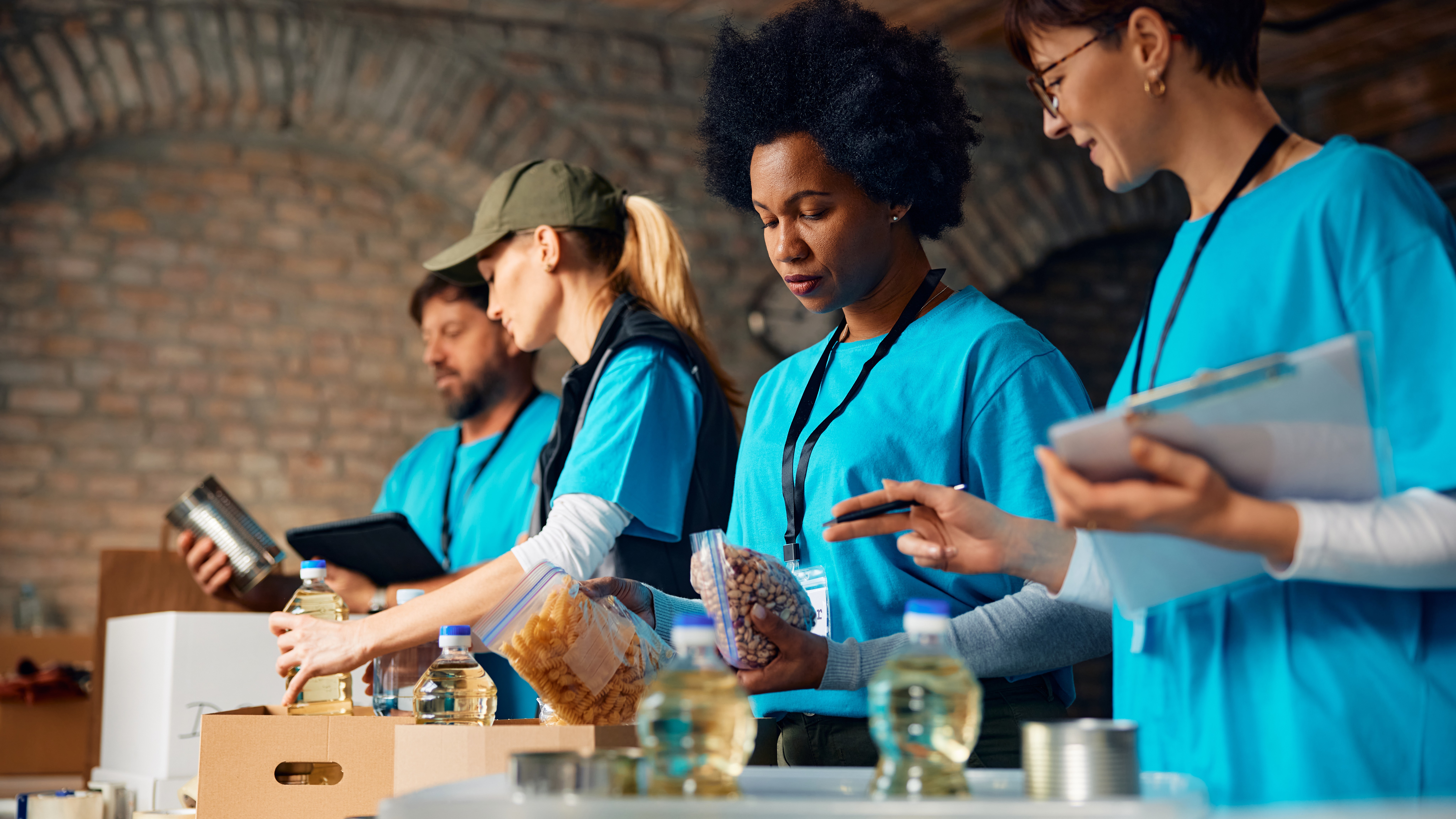 Group of volunteers packing donated food at humanitarian aid center.