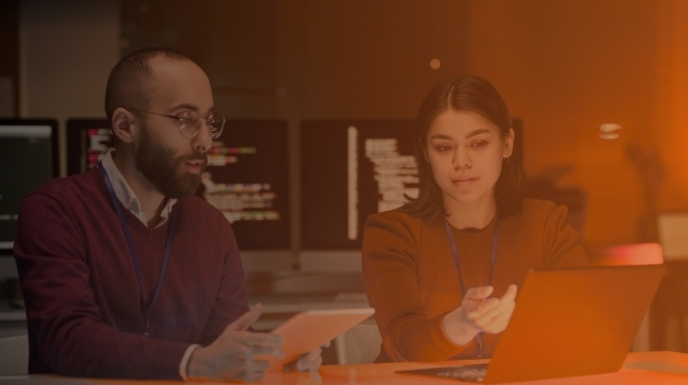 Portrait of young woman as female IT security expert using laptop with male colleague