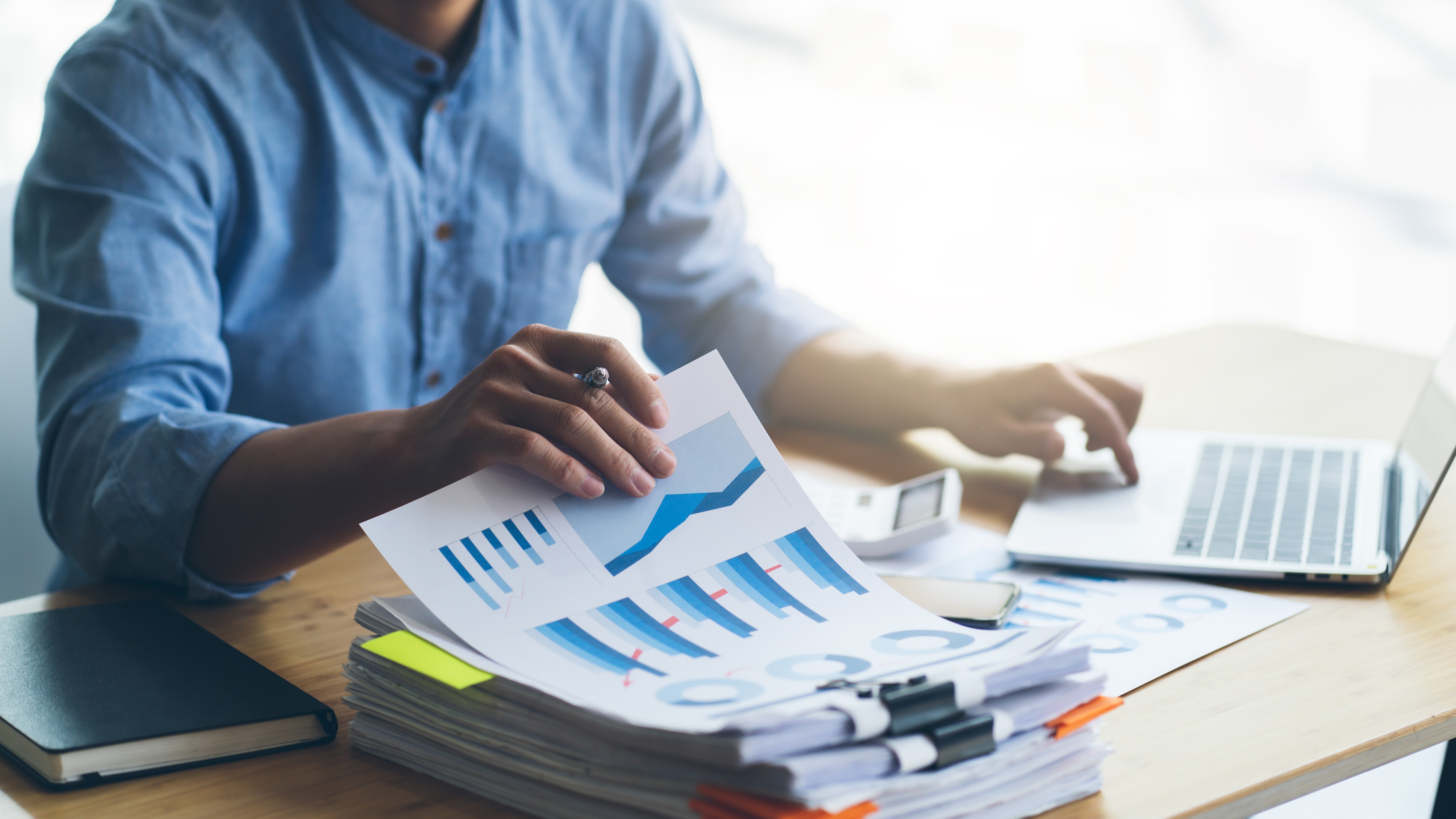 Businessman hands working in Stacks of paper files for searching information on work desk home office, business report papers,piles of unfinished documents achieves with clips indoor.